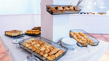 A buffet table with various baked goods, including croissants and pastries, arranged in wire baskets.