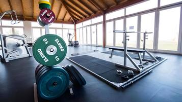 Ein Fitnessstudio mit Gewichte, Laufband und großen Fenstern.