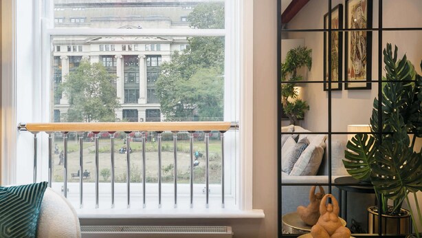A room with a large window overlooking a building and a balcony.