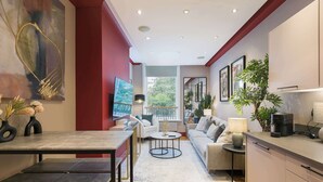 A modern living room with a dining area, a sofa set, a coffee machine, and a large abstract painting on the wall.