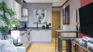 A modern kitchen with white cabinets, a central island, and a large painting on the wall.
