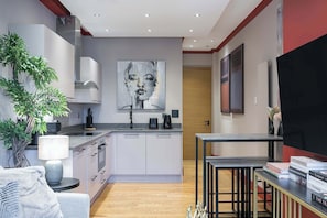 Une cuisine moderne avec des meubles blancs, un îlot central et un grand tableau accroché au mur.