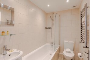 A modern bathroom with a bathtub, toilet, and a glass shower enclosure.