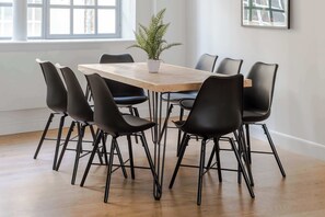 Un coin repas avec une table en bois, des chaises noires et une plante en pot.