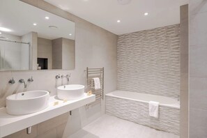 Une salle de bain moderne avec deux lavabos, un grand miroir et une baignoire.