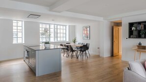 A spacious kitchen with a dining area, wooden flooring, and large windows. - Farringdon 3-Bed · 2 En-Suites · Lift · Sleeps 8 (London)