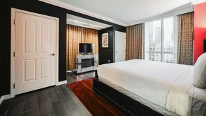 Een hotelkamer met een groot bed, een televisie en uitzicht op de stad.