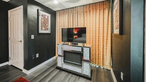 Een moderne woonkamer met een open haard, een televisie en een kunstwerk in een lijst aan de muur.
