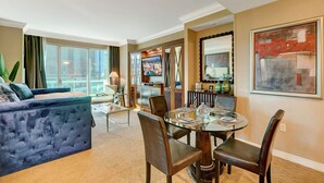 A modern hotel room with a living area, dining space, and a large window offering a city view. - SVS: Designer Remodeled 1BD | Strip View Balcony | Signature at MGM (Las Vegas)