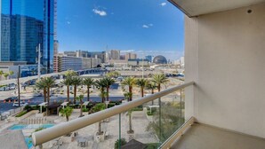 Un balcon offrant une vue sur le paysage urbain, les palmiers et un bâtiment moderne en construction.