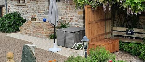 A stone building with a garden patio, outdoor seating, and a wooden fence.