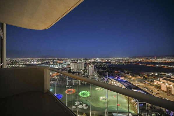 A night view from a high-rise balcony overlooking a cityscape with illuminated streets and buildings. - 1BD/2BA • Balcony • No Resort Fee • Free Parking E24I2 (Las Vegas)