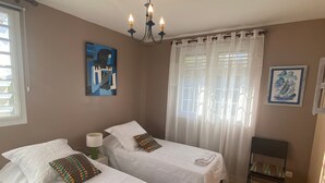 Een kamer met twee bedden, een stoel, een kroonluchter en kunstwerken aan de muren.
