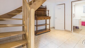 A wooden staircase with a small table at the bottom landing. - Peaceful country house with enclosed garden (Muneville-sur-Mer)