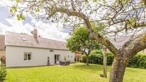 A white house with a covered patio, a lawn, and a tree with yellow lichen. - Peaceful country house with enclosed garden (Muneville-sur-Mer)