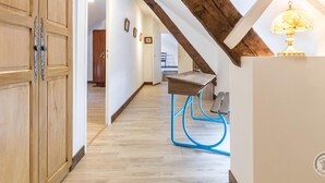A hallway with wooden doors, a desk with a blue chair, and a lamp. - Peaceful country house with enclosed garden (Muneville-sur-Mer)