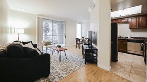 Uma sala de estar moderna com um sofá, uma televisão e um espaço de jantar com cadeiras e uma mesa.