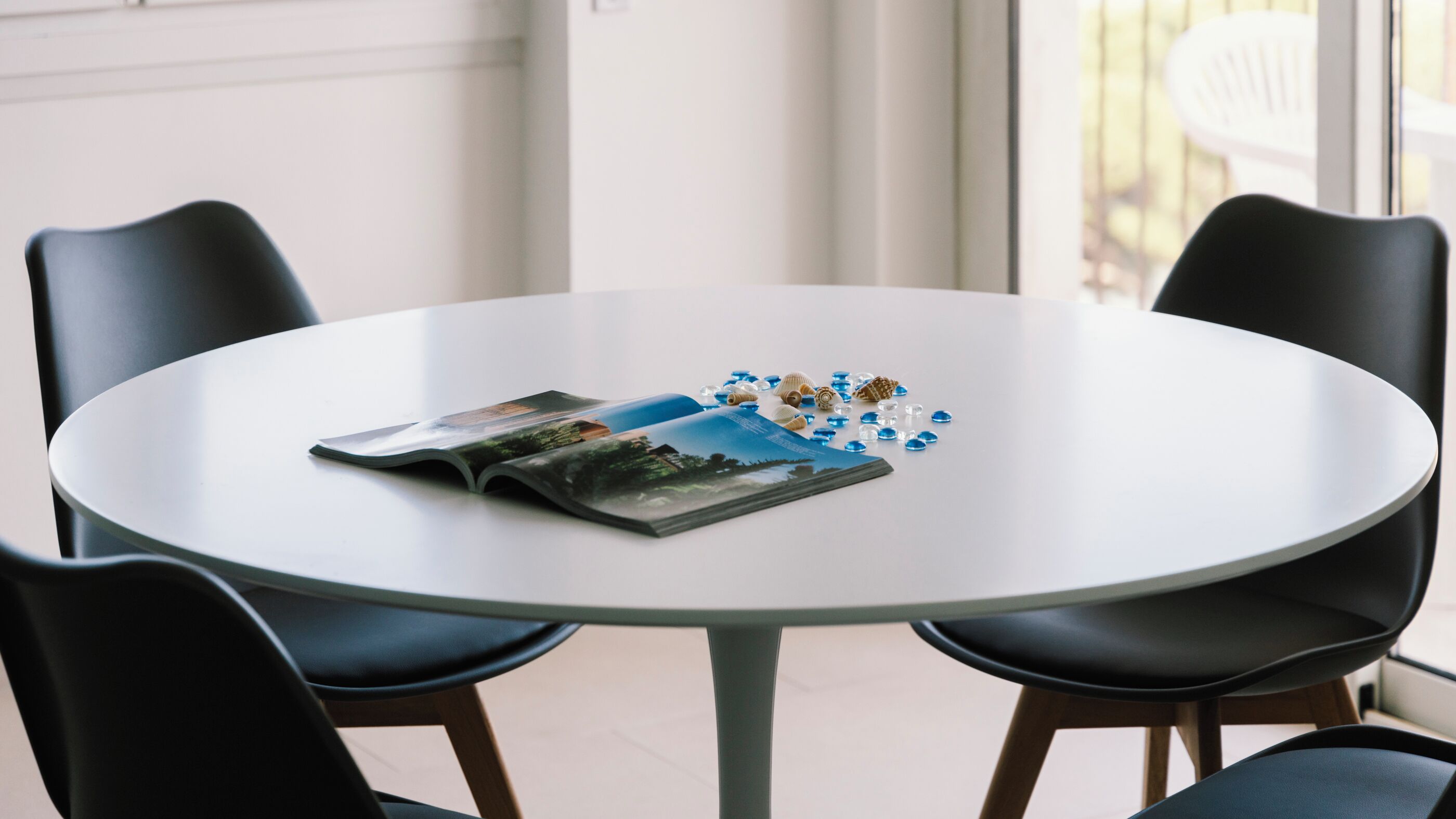 A round table with a magazine and seashells.