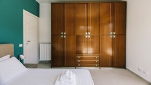 A bedroom with a large wooden wardrobe, a bed with white linens, and a white radiator. - Italianway - Le Terrazze sul Mare (Diano Marina)