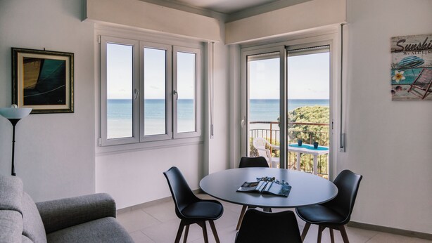A balcony with a view of the sea, a round table with chairs, and a framed picture on the wall. - Italianway - Le Terrazze sul Mare (Diano Marina)