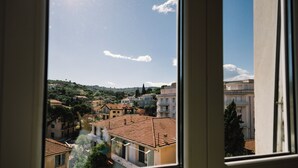 A view of a residential area with terracotta-tiled roofs, a river, and a hill in the background. - Italianway - Le Terrazze sul Mare (Diano Marina)
