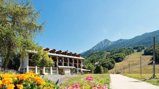 Un hotel dallo stile architettonico alpino tradizionale, con un cortile centrale e numerosi balconi.