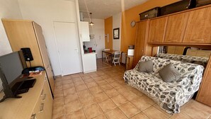 A compact living space with a kitchenette, a dining area, and a sofa.