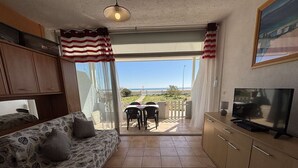 A compact living space with a sofa, TV, and a view of the sea.