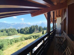 Un balcon en bois offrant une vue sur un paysage montagneux.