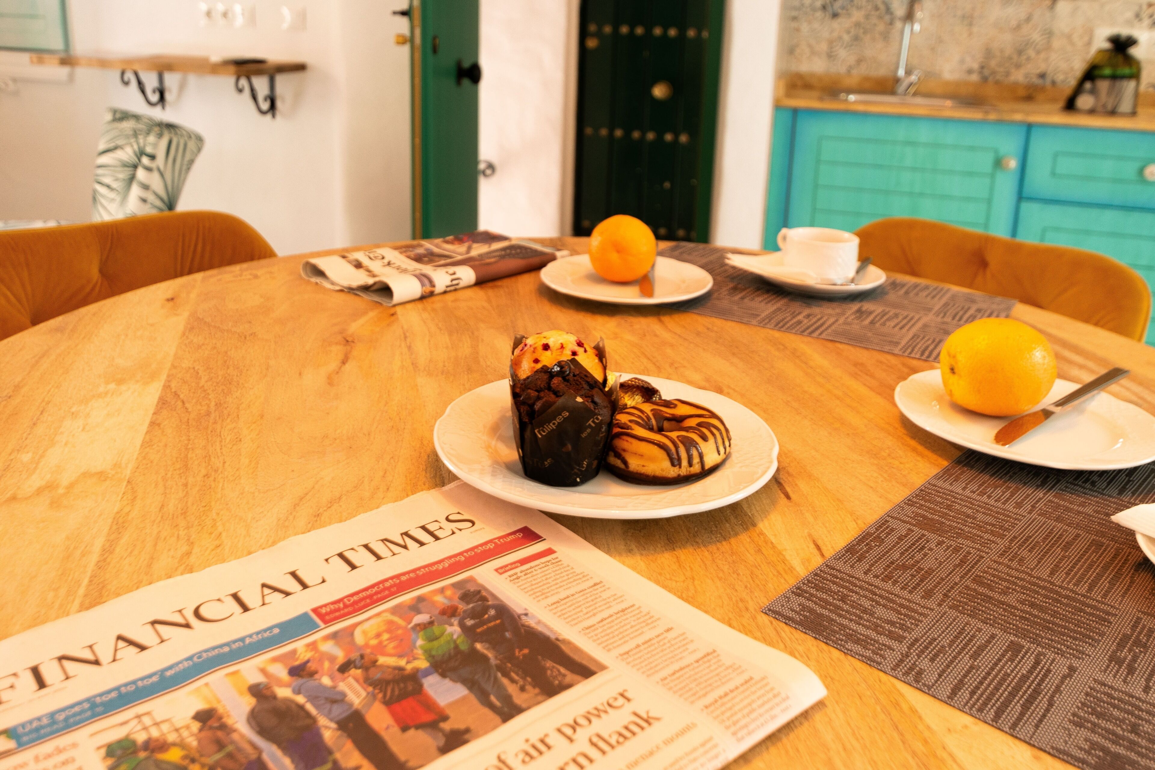 Una mesa de comedor con un periódico, platos de comida y una taza.
