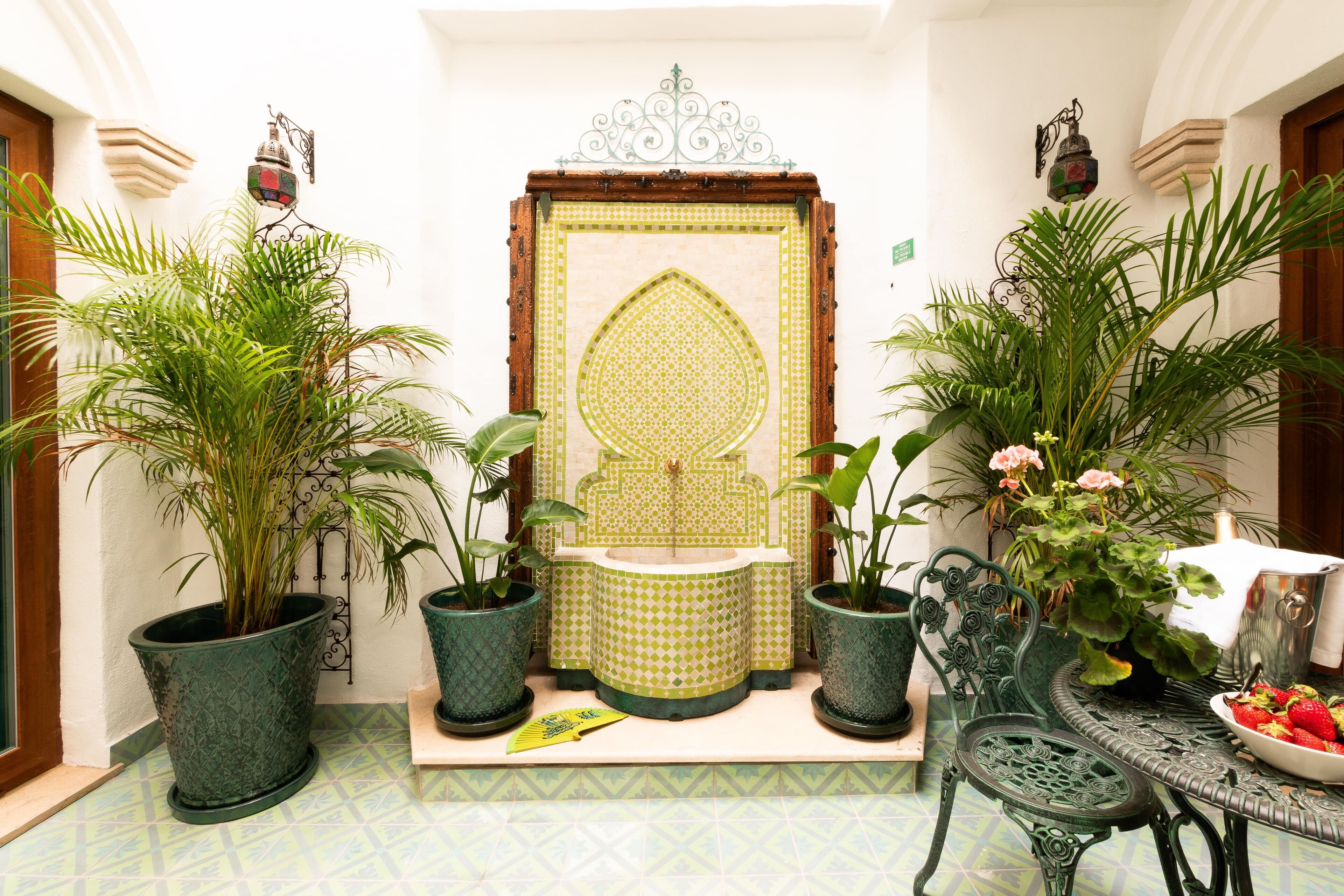 A traditional interior with a decorative door, potted plants, and a table with a bowl of fruit.