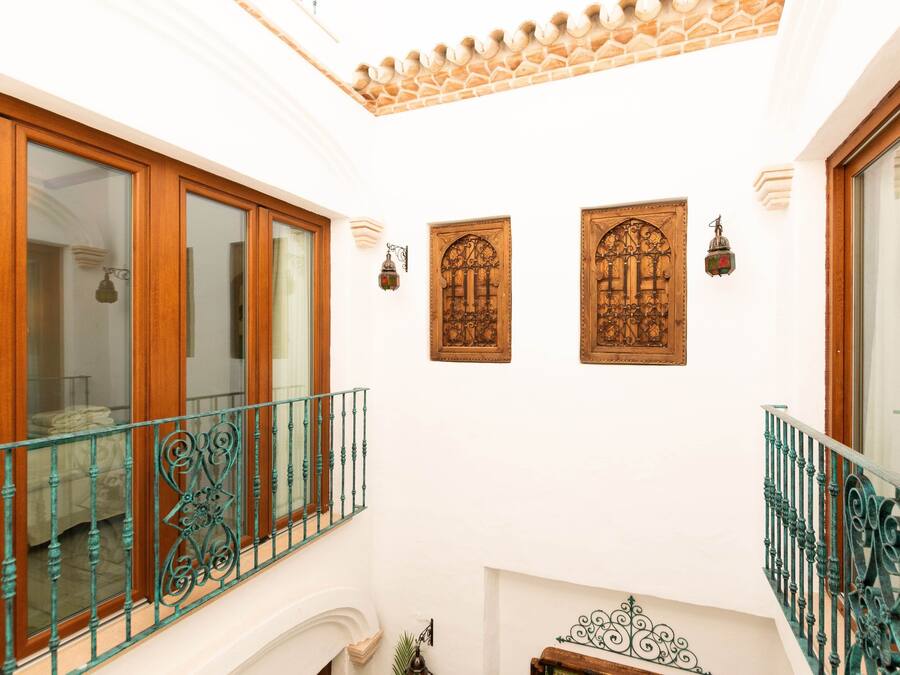 A hotel interior with a balcony, wooden doors, and decorative wall sconces.