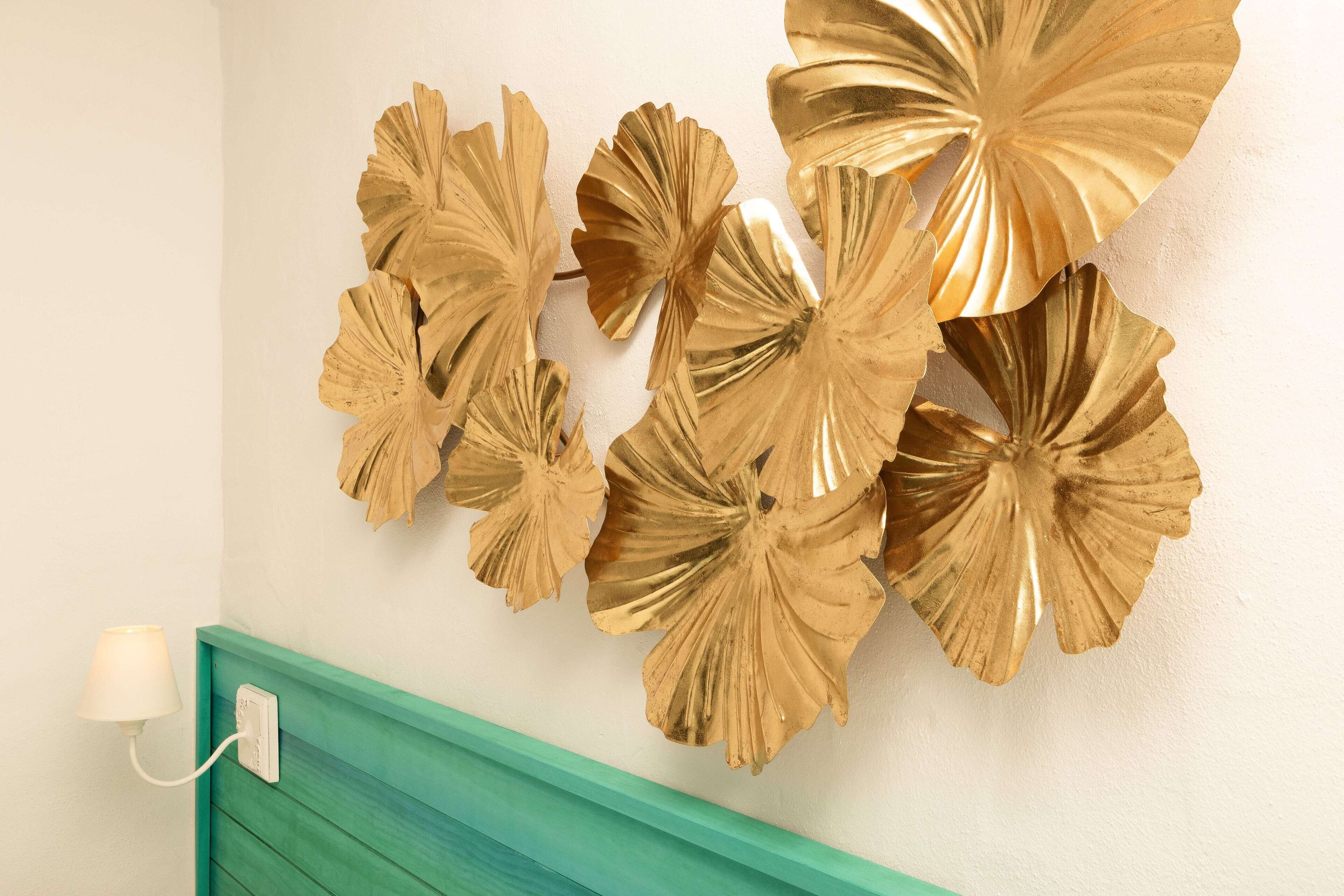 Una pared con decoraciones de hojas doradas y una sección inferior color turquesa.