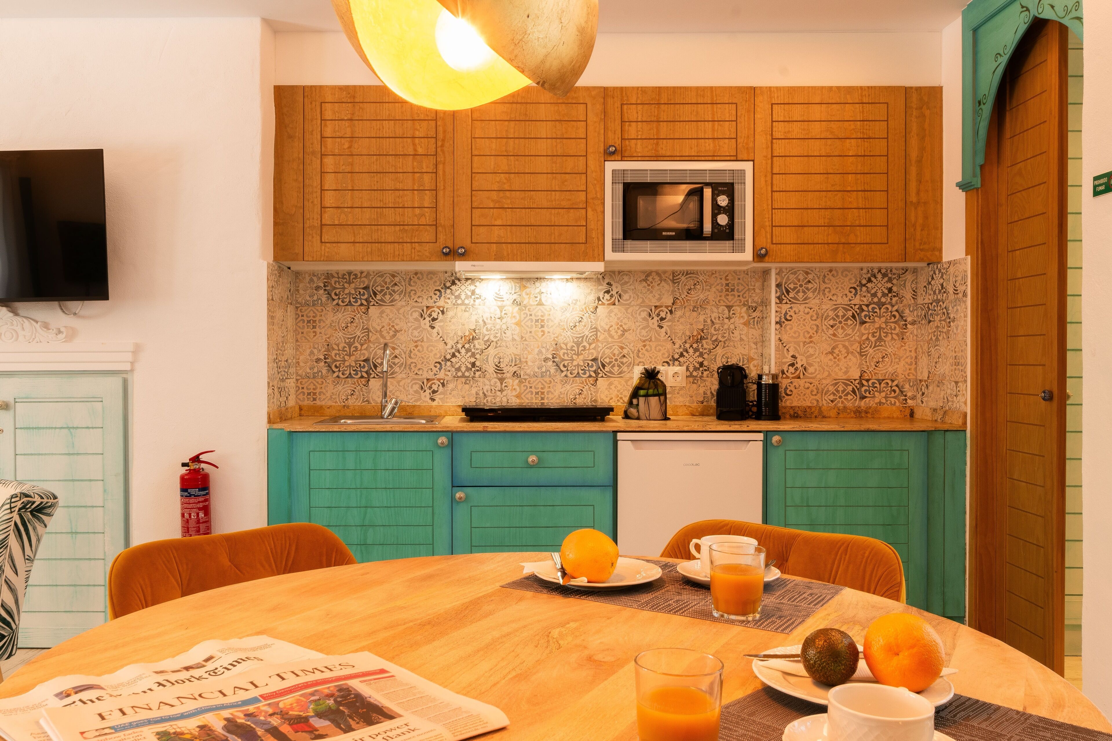 A kitchen with wooden cabinets, a microwave, and a dining table with breakfast items.