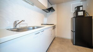 Eine Küche mit weißen Schränken, einer Edelstahl-Spüle, einem schwarzen Kühlschrank und einer Mikrowelle darüber.