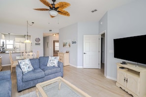 A living room with a sofa, television, and a ceiling fan. - Ocean Village Club Condo Q31 (St. Augustine)