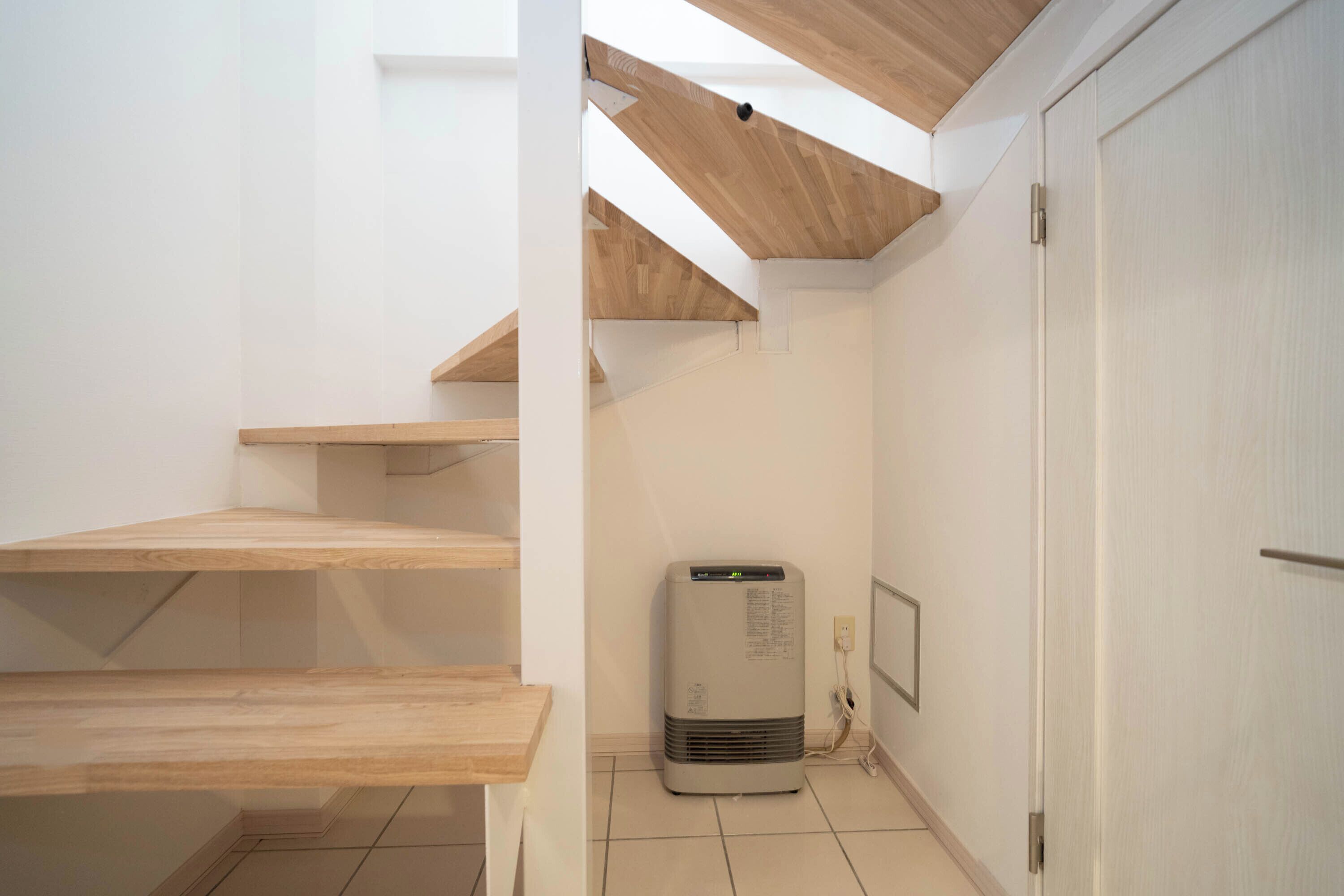 A staircase with wooden steps leading to a landing, a white door, and a wall-mounted air conditioner.