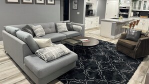 Un salon moderne avec un canapé gris, une table basse et un tapis noir.
