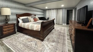Une chambre à coucher avec un grand lit, un bureau, une télévision et un tapis à motifs.