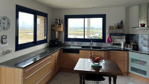 Una cocina moderna con armarios de madera, encimera negra y ventana con vistas al campo.