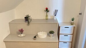 Ein kleiner, kompakter Raum mit Holzboden, einer weißen Bank und einem weißen Schrank mit Schubladen.