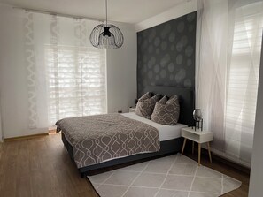 Ein modernes Schlafzimmer mit einem großen Bett, einem Nachttisch und einer Hängelampe.