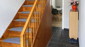 Eine Holztreppe mit grauen Teppichstufen, die zu einer Zwischenebene führen.