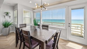 A dining area with a large wooden table, chairs, and a ceiling light fixture. - Seawinds 9 | Renovated Gulf-Front Escape (Mramar Beach)