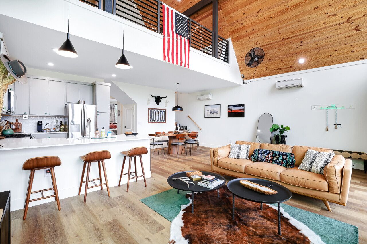 A spacious living area with a high ceiling, a dining area, and a kitchen.
