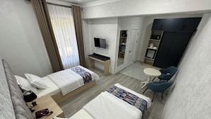 A hotel room with two beds, a desk, a TV, a small table with chairs, and a wardrobe. - DSF GARDEN HOTEL (Tashkent)