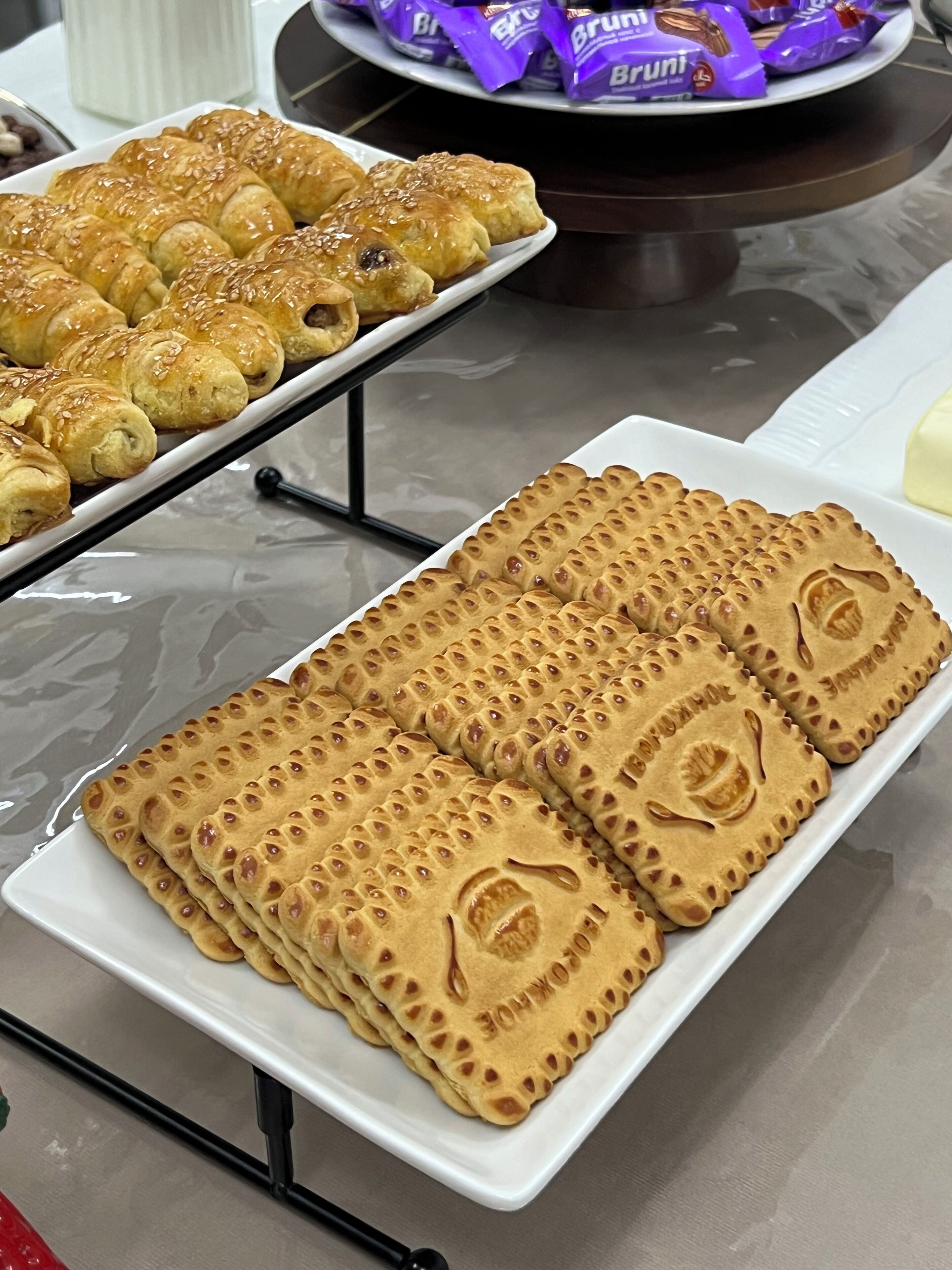Une table de buffet proposant divers types de viennoiseries, notamment des croissants et des pâtisseries rectangulaires ornées de motifs en relief.