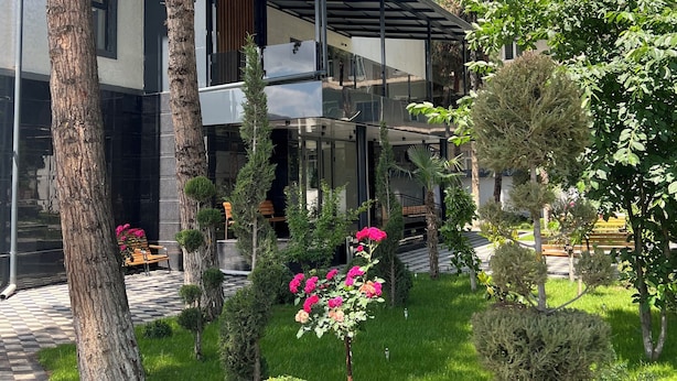 A modern two-story building with a covered outdoor area, surrounded by well-maintained greenery and a paved walkway. - DSF GARDEN HOTEL (Tashkent)