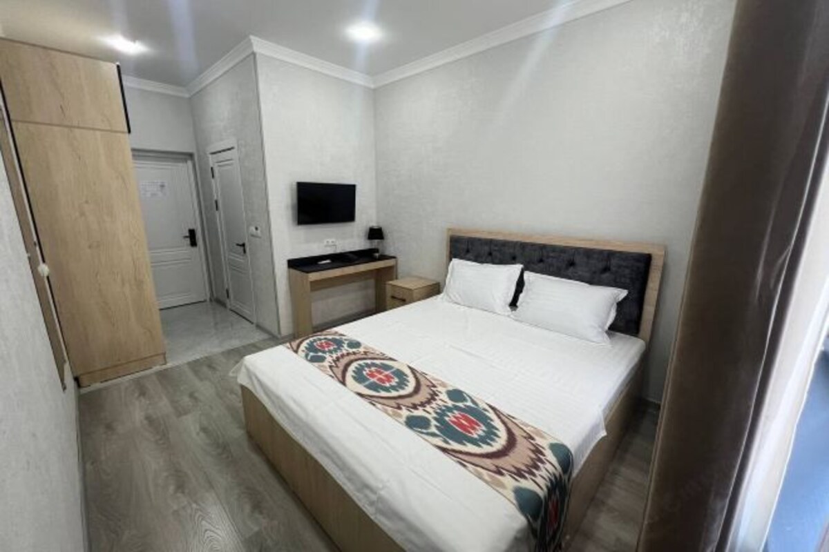 A bedroom with a bed, a desk, a TV, and a wardrobe.