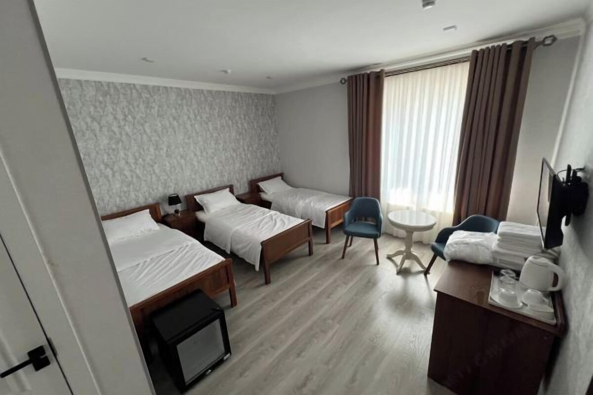 A hotel room with two beds, a desk with a chair, a small table, and a TV.